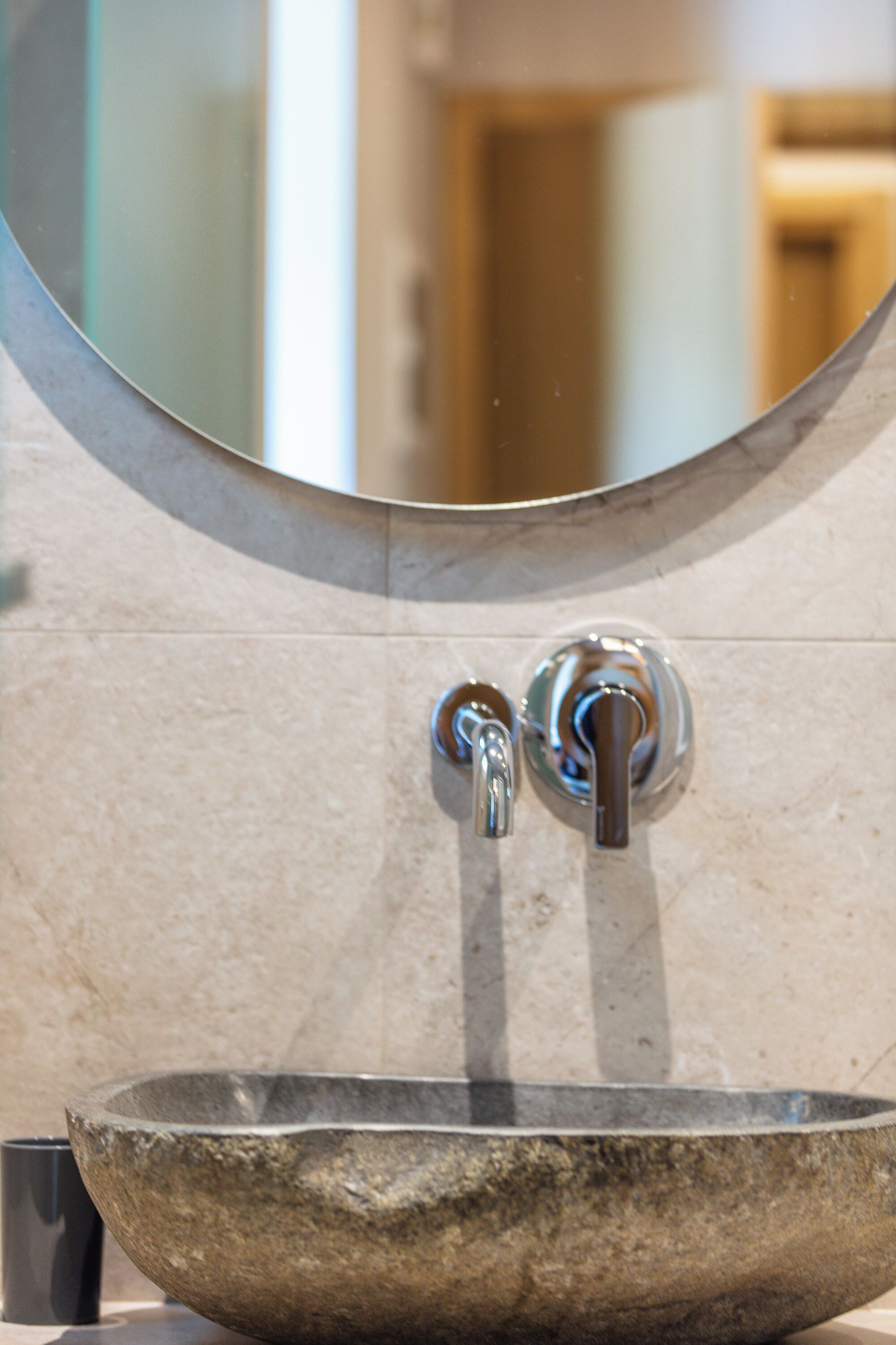 A stone basin with a faucet and a mirror above it.