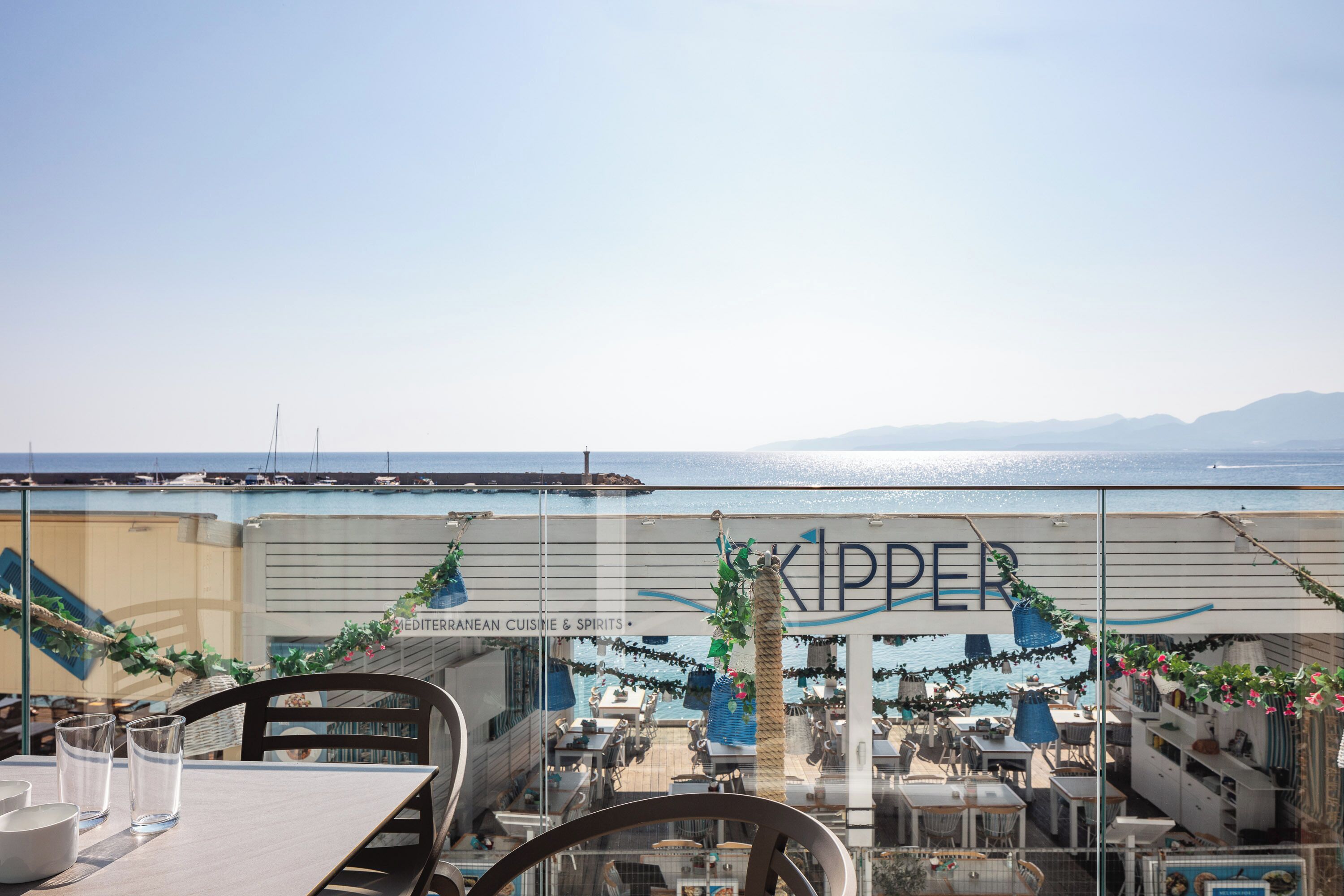 Restaurante con vista al mar, con mesas al aire libre y un letrero que dice 'KIPPER'.