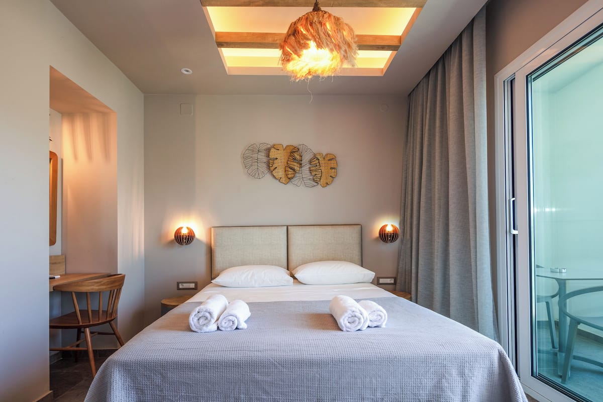 Una habitación de hotel con una cama, dos mesitas de noche, un escritorio y una silla.