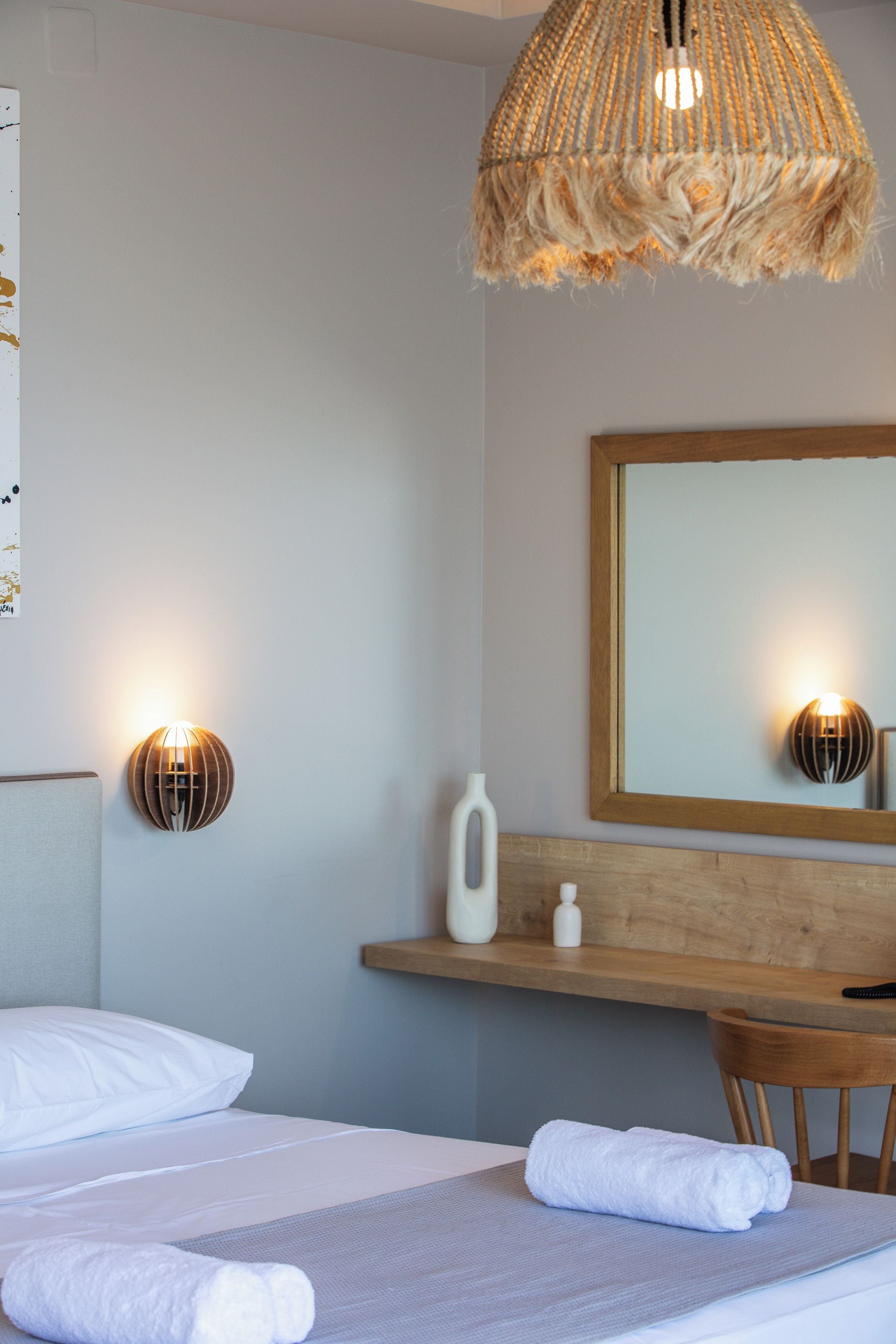 Une chambre d’hôtel avec un lit, des lampes de chevet, un miroir, une table de chevet en bois et une chaise.