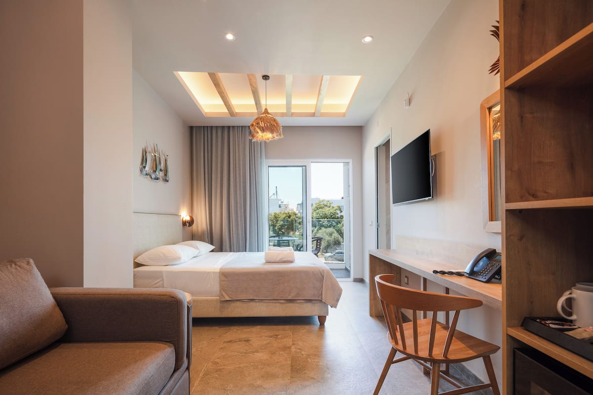Una habitación de hotel moderna con cama, escritorio, silla, televisión y balcón con vistas.