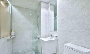 A modern bathroom with a glass shower enclosure, a white sink, and a toilet. - Seoul Hotel TAO (Seoul)