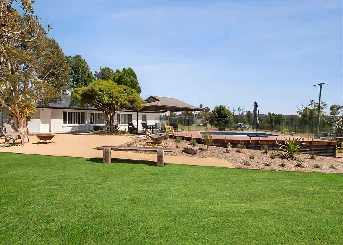 Una casa con piscina, césped y mobiliario de exterior.