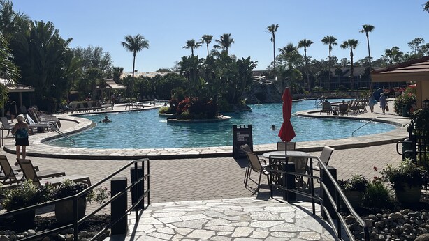 A pool area with lounge chairs and a sign indicating a swimming sunset set. - Vacation in Paradise, Naples, FL (Naples)