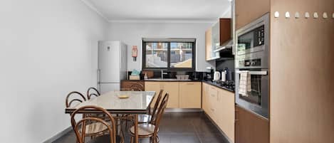 A modern kitchen with a dining area, featuring a large window, stainless steel appliances, and a clean, minimalist design.