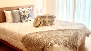 A neatly made bed with a quilted duvet, a woven throw blanket, and a decorative basket. - Villa Bella (Machico)