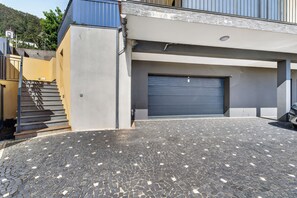 A modern building with a garage, a staircase, and a paved driveway. - Villa Bella - Mountain views & Outdoor living (Machico)