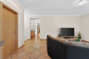 A modern living room with a sofa, TV, and a wooden cabinet. - Villa Bella - Mountain views & Outdoor living (Machico)