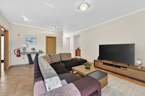 A modern living room with a sectional sofa, a flat-screen TV, and a coffee table. - Villa Bella - Mountain views & Outdoor living (Machico)