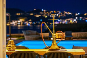 A poolside setting with a hookah, a golden decorative bowl, and lounge chairs.