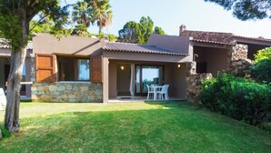 A modern house with a stone facade, a patio with a table and chairs, and a well-maintained lawn.