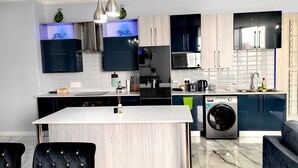 A modern kitchen with a central island, built-in appliances, and a dining area with upholstered chairs.