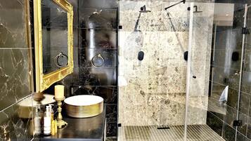 Une salle de bain avec un grand miroir, un lavabo rond et un espace douche.