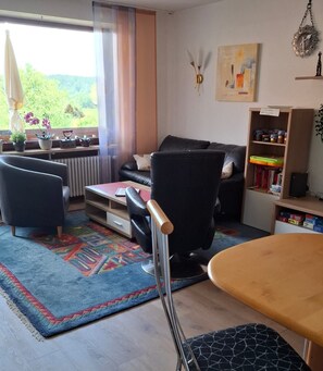 Un salon moderne comprenant un canapé, des fauteuils, une table basse et une bibliothèque.