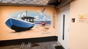 A mural of a boat on water with a seagull flying above, and the words "Just Live" and "Welcome" on the wall. - Apartment "Just Live" at the mill pond (Wismar)
