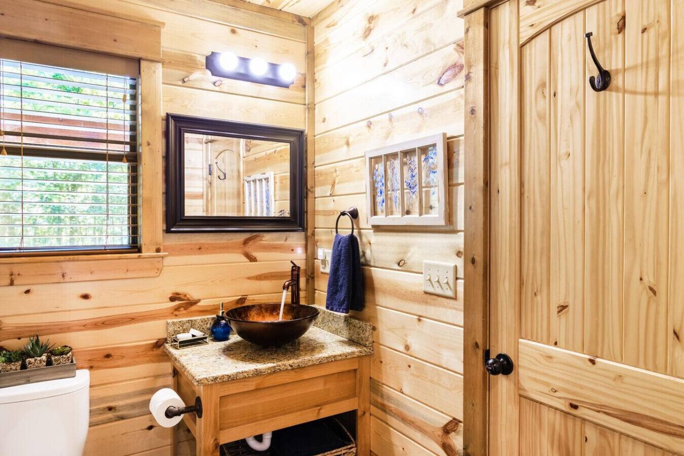 A wooden cabin bathroom with a sink, mirror, and towel rack.