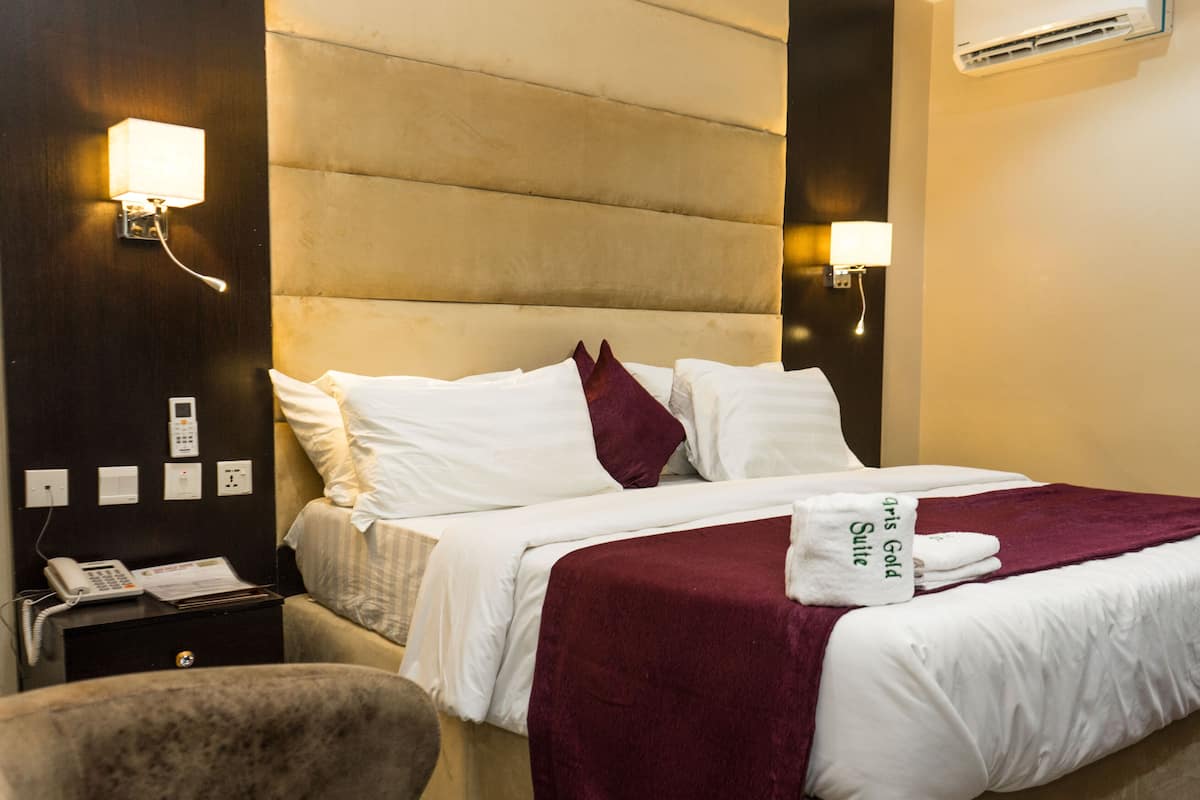 A hotel room with a large bed, a bedside table with a phone, and a wall-mounted air conditioner.