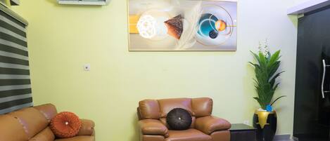 Una sala de estar con dos sofás de cuero, una mesa de centro, un cuadro en la pared y una planta en maceta.