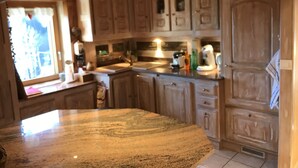 A kitchen with wooden cabinets, a granite countertop, and a window with curtains. - Family mountain chalet, Close to the Brasses ski slopes (Saint-Jeoire)