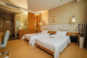 Habitació d'hotel amb dos llits, un escriptori, una cadira, una tauleta de nit i un vas amb flors.
