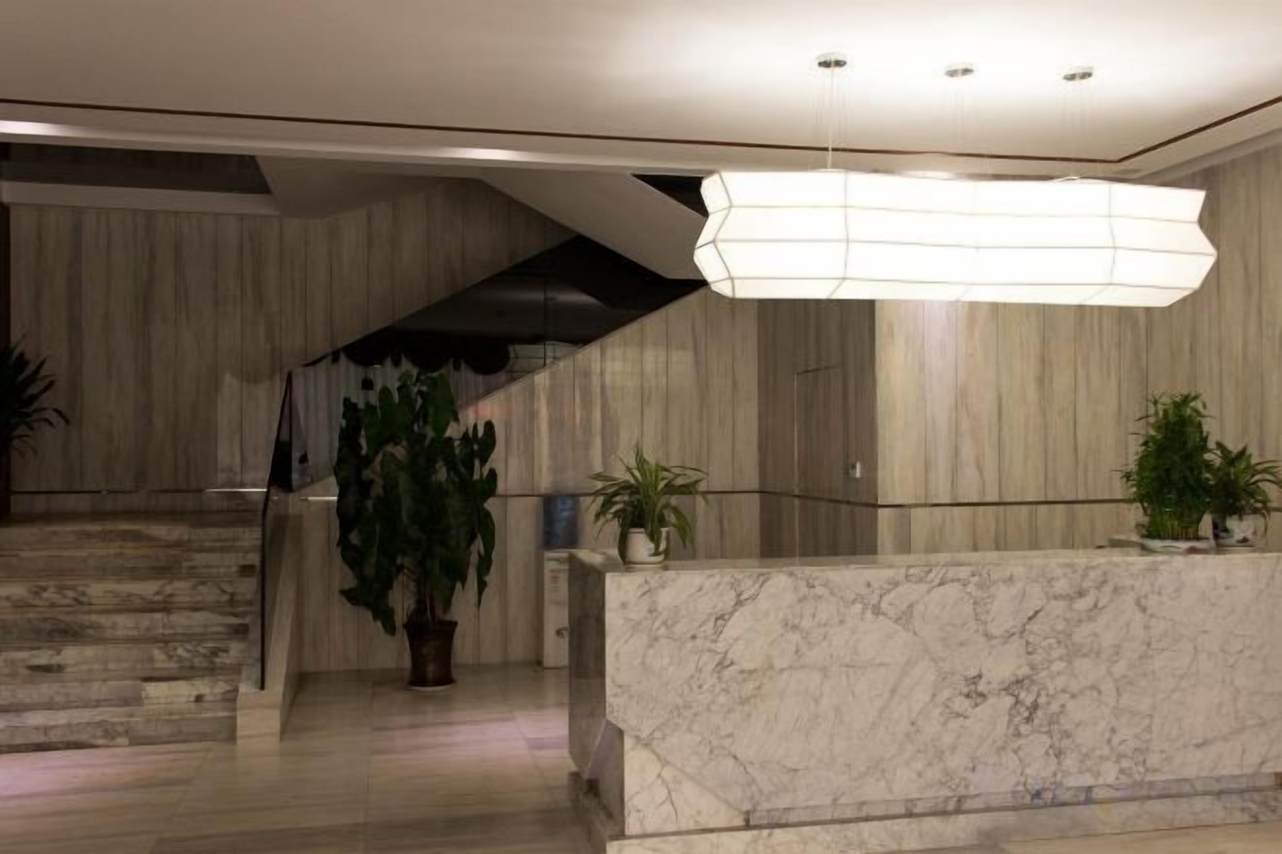 En reception med en marmordisk, trappe og en hængende lampe.