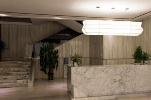 A reception area with a marble counter, a staircase, and a hanging light fixture. - Guangzhou No.6 Inn (Panyu District Ha Street Branch) (Guangzhou)