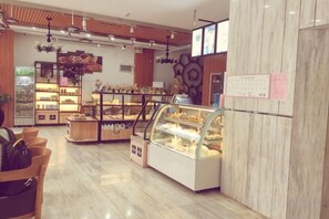 A bakery interior with display cases, shelves, and a seating area. - Guangzhou No.6 Inn (Panyu District Ha Street Branch) (Guangzhou)