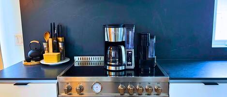 A kitchen with a stove, oven, and coffee maker.