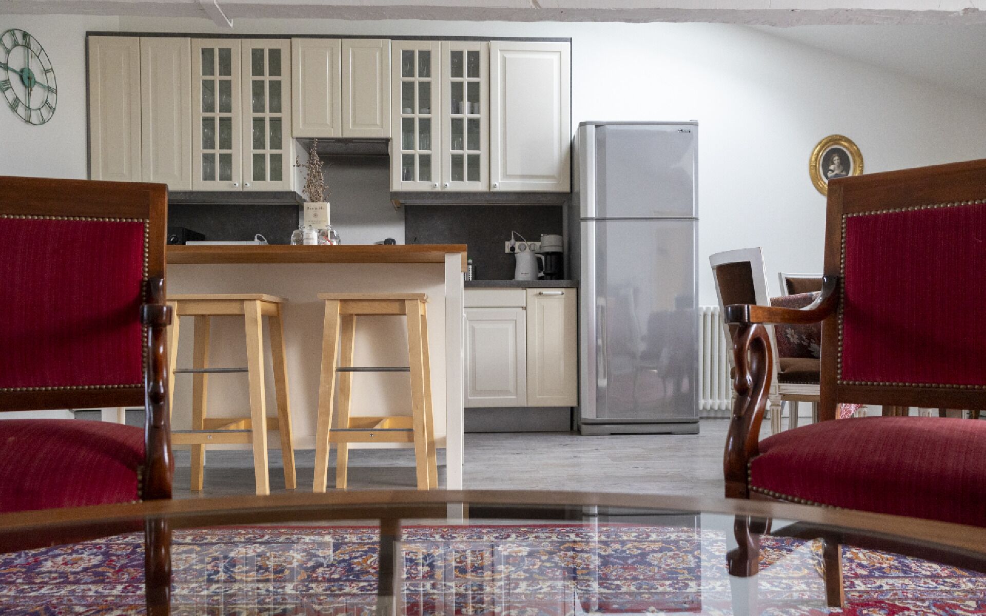 A compact kitchen with white cabinets, a refrigerator, and a bar area with stools.