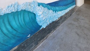 A hallway with a wall decorated with colorful letters spelling "Odeon" and a painted wave design below. - 3 bd condo with rooftop across the street from beach! (Rio San Juan)