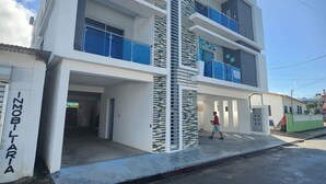 A modern multi-story building with balconies and a central vertical feature. - 3 bd condo with rooftop across the street from beach! (Rio San Juan)