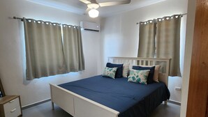 A bedroom with a bed, curtains, a ceiling fan, and an air conditioning unit. - 3 bd condo with rooftop across the street from beach! (Rio San Juan)