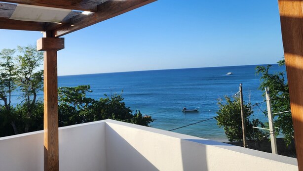 A wooden balcony with a view of the sea. - 3 bd condo with rooftop across the street from beach! (Rio San Juan)