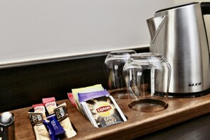 Eine Ablageplatte mit Lipton Teebeuteln, einer KLEO Kaffeemaschine und zwei Gläsern.