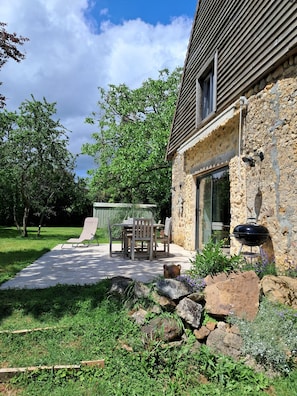 Une maison en pierre avec un patio, du mobilier d’extérieur et un barbecue.