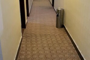A narrow hallway with patterned carpet and a trash can. - Xinfuhua Business Hotel (Taishan)