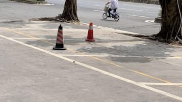 Una zona pavimentada con conos de tráfico y un ciclista a lo lejos.