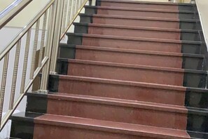 Um lance de escadas com corrimão à esquerda e borda preta à direita.