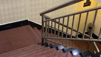 Una escalera con barandillas metálicas y escalones negros que conducen a un piso inferior.