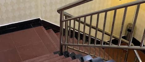 Un escalier avec des rampes en métal et des marches noires menant à un étage inférieur.