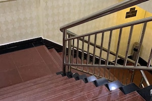 Una escalera con barandillas metálicas y escalones negros que conducen a un piso inferior.