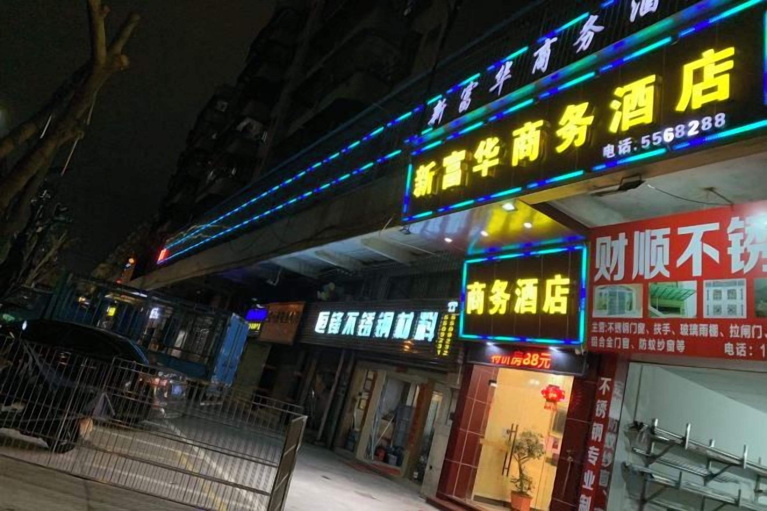 A hotel with illuminated signage, a visible entrance, and a storefront with a red awning.