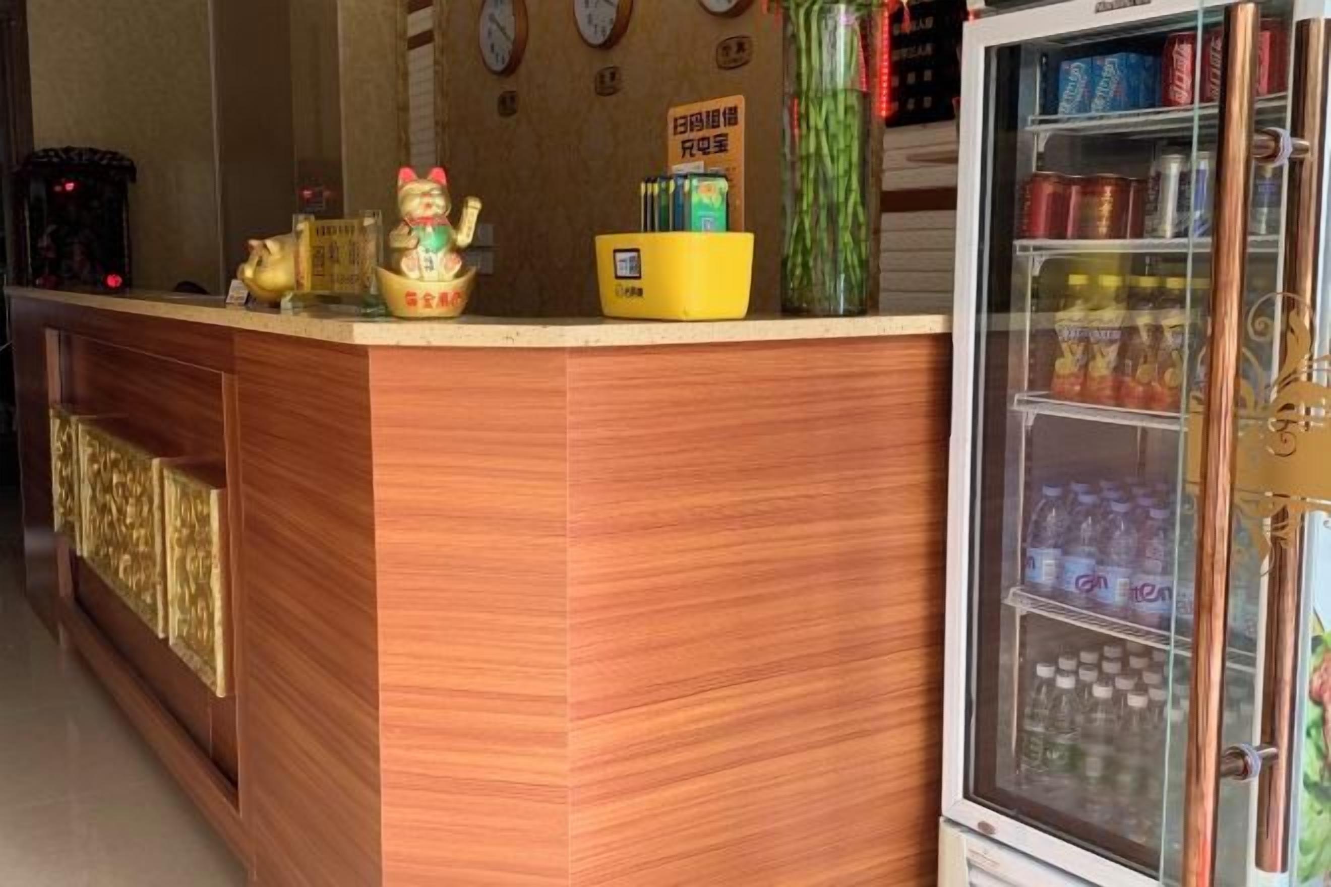 A reception desk with a refrigerator stocked with beverages, a small yellow bowl, and a decorative item.