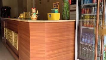 A reception desk with a refrigerator stocked with beverages, a small yellow bowl, and a decorative item.