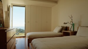Un dormitorio con dos camas, un aparador, una mesita de noche, una lámpara y un florero con flores.