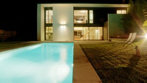 Una casa moderna con piscina, terraza cubierta e interior bien iluminado.