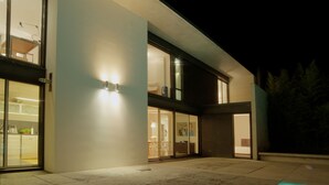 Una casa moderna con piscina, ventanas amplias e iluminación exterior destacada.