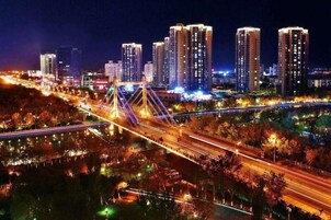Un paisaje urbano nocturno con rascacielos iluminados, un puente y una carretera bien iluminada.