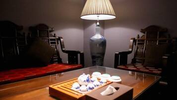 A dimly lit room with a wooden table set for tea, a lamp, and traditional furniture.