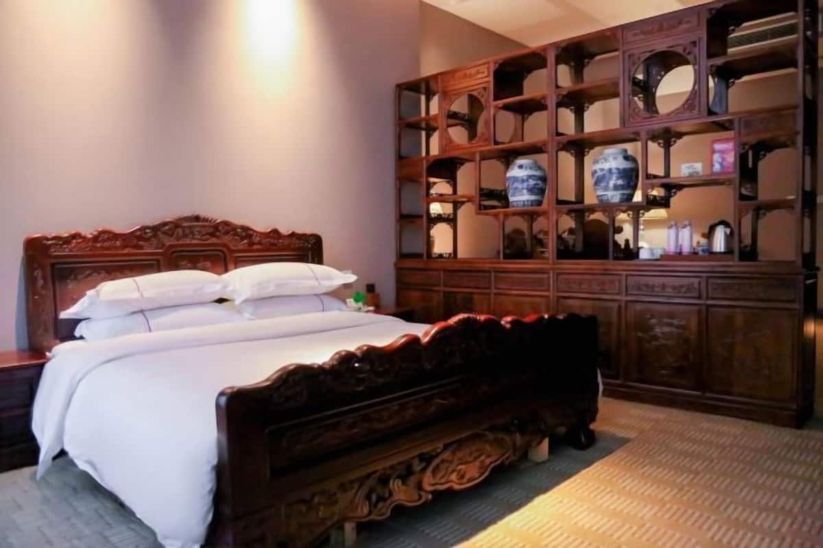 A bedroom with a wooden bed, a nightstand, and a wooden cabinet with shelves.